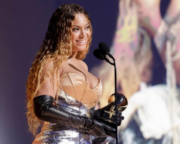 Nominacje do Grammy 2025. Na zdjęciu 32. krotna zwyciężyni Beyonce podczas ceremonii. W ręku trzyma statuetkę w postaci gramofonu, na jej twarzy maluje się uśmiech, a ubrana jest w srebrno - beżową suknię wieczorową