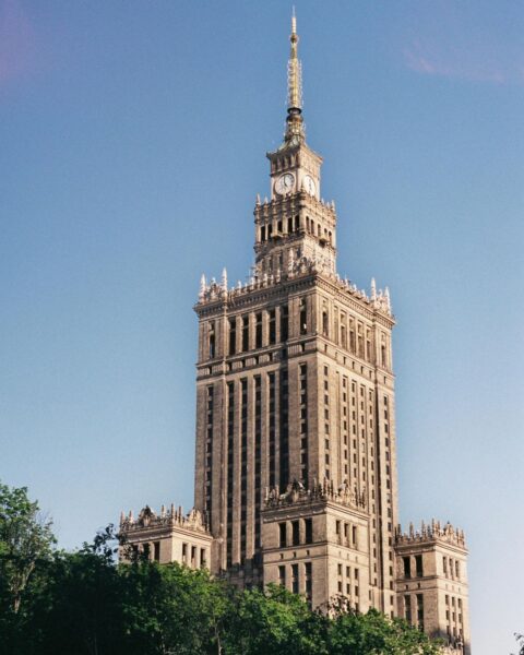 Co robić w ferie zimowe w Warszawie? Widok z dołu na Pałac Kultury i Nauki w Warszawie na tle jasnego, bezchmurnego nieba.