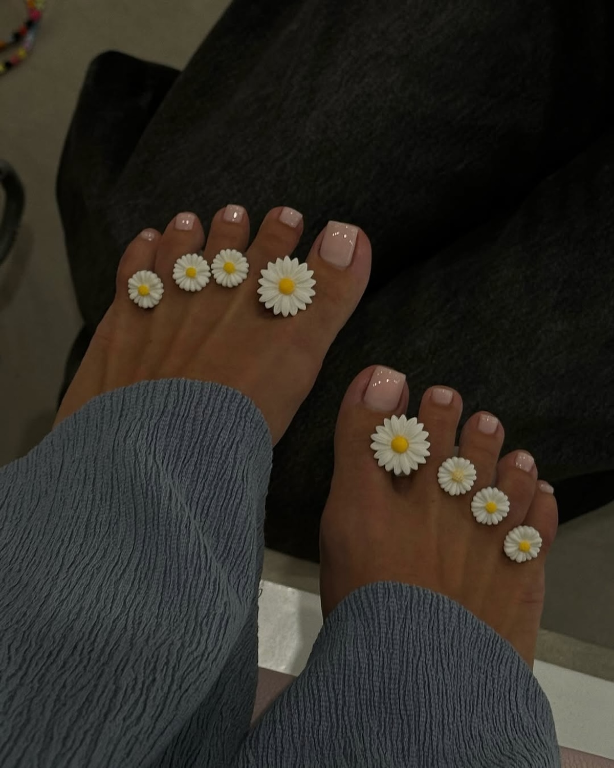 Pedicure na wiosnę 2025 w stylu boho z motywem stokrotek – Stopy z naturalnym, jasnym lakierem na paznokciach ozdobione miniaturowymi stokrotkami, tworzącymi delikatny, kwiatowy akcent. Idealny pedicure na wiosnę 2025, który dodaje dziewczęcego uroku i lekkości.