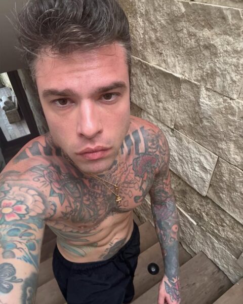 Fedez zdrada: Mężczyzna ze smutnymi oczami robi sobie selfie na tle kamiennego tła.