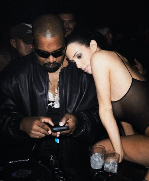 Bianca Censori i Kanye West uchwyceni w klubowym klimacie – ona w czarnej, prześwitującej sukience, on w skórzanej kurtce i okularach przeciwsłonecznych, patrzy na telefon. Bianca opiera się o niego w intymnym geście. Bianca Censori – kim jest? W przestrzeni publicznej często widziana u boku znanego rapera, a ich relacja przyciąga uwagę mediów.