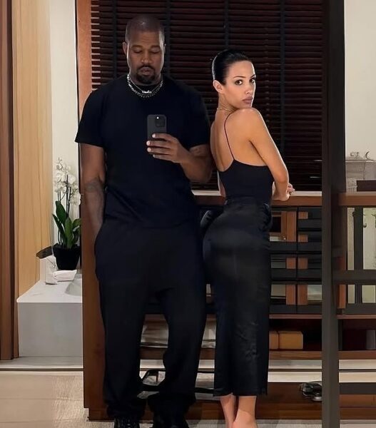 Kanye West i jego nowa partnerka w lustrzanym selfie – Artystyczne ujęcie, na którym Kanye West ubrany w czarny t-shirt i spodnie pozuje do selfie z tajemniczą kobietą w eleganckiej, czarnej sukience. Zdjęcie podkreśla minimalistyczny, nowoczesny styl Westa, który po rozwodzie z Kim Kardashian wciąż pozostaje ikoną mody.