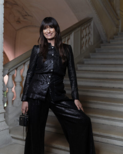 Caroline de Maigret na paryskiej met gali 2025. Kobieta w czarnych połyskujących spodniach i dopasowanej marynarce, pozuje na schodach, emanując elegancją i stylem.