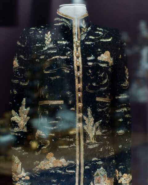 Czarna, bogato zdobiona marynarka CHANEL z misternym złotym haftem i wysokim kołnierzem na wystawie. Marynarka jest częścią ekspozycji LOUVRE COUTURE. Art and Fashion: Statement Pieces.