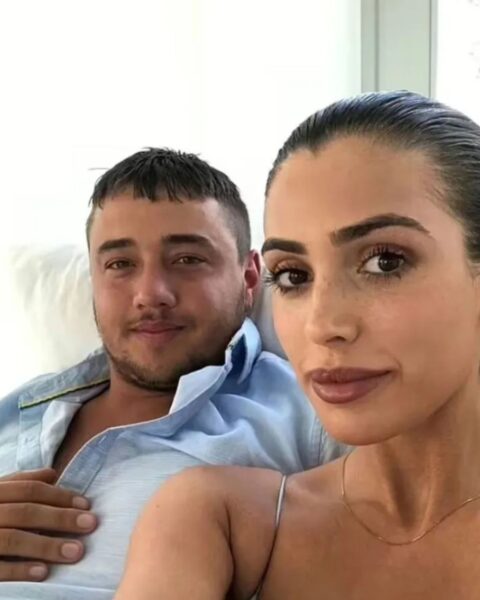 Zdjęcie Bianci Censori i jej byłego chłopaka Nicka Forgiane w 2020 roku przed pandemią. Siedzą na kanapie i kobieta robi im selfie. Ma ciemne, związane włosy. Mężczyzna ubrany jest w błękitną koszulę rozpiętą pod szyją.