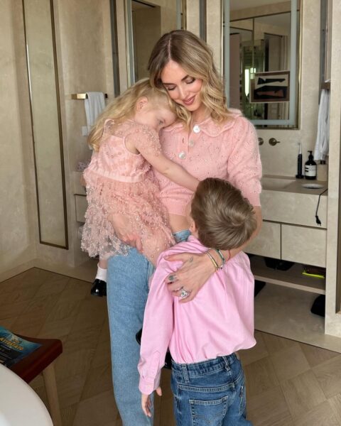 Chiara Ferragni z córką i synem.
Kobieta w blond włosach trzyma na rękach dziewczynkę w różowej sukience. Przy niej stoi chłopiec w różowej koszuli, patrzący na nią.