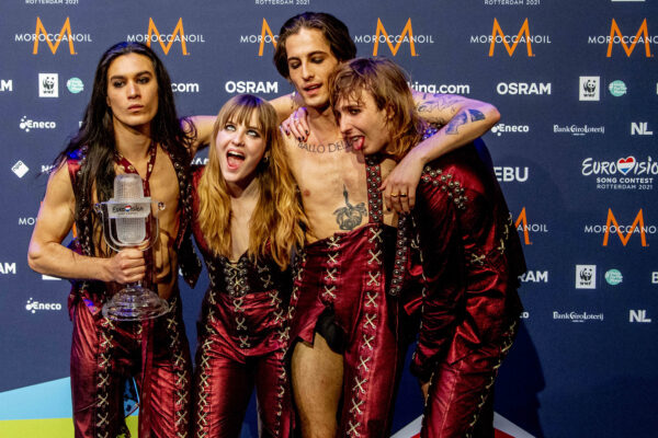 Zespół Måneskin z Włoch świętuje zwycięstwo w Konkursie Piosenki Eurowizji 2021 w Rotterdamie, prezentując swoją charakterystyczną estetykę glam rocka i buntowniczego stylu, który przyniósł im międzynarodowy rozgłos – na zdjęciu członkowie grupy trzymają trofeum Eurowizji i pozują na ściance prasowej.