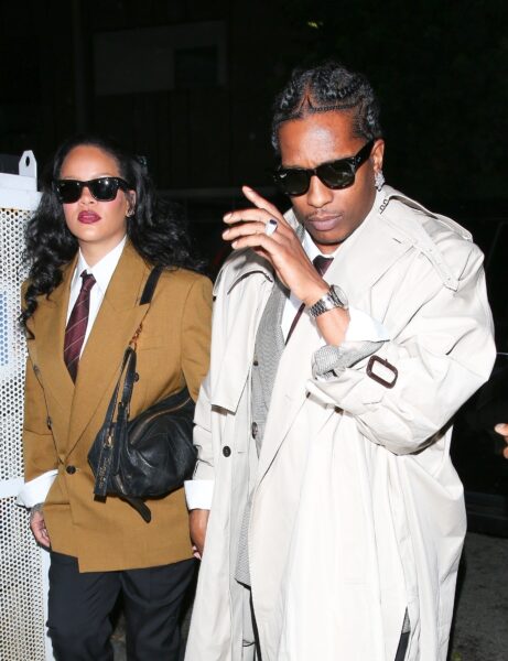 Rihanna w brązowej marynarce, białej koszuli i bordowym krawacie w duecie z A$AP Rockym w beżowym trenczu i garniturze – stylizacje w duchu „officecore” z nutą nowoczesnego glamouru, uchwycone podczas wieczornego wyjścia pary.