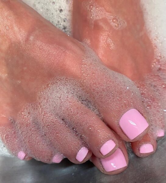 Delikatny różowy pedicure zatopiony w pianie kąpielowej – ujęcie idealne dla miłośniczek romantycznych, pastelowych odcieni i relaksu w domowym spa.
