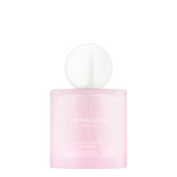 Różowa butelka perfum Jo Malone London z kolekcji Sakura Cherry Blossom Cologne, o matowym wykończeniu i minimalistycznym designie; na górze okrągła, biała zatyczka przypominająca porcelanową kulę – elegancki flakon w stylu wiosennej świeżości inspirowany japońskimi kwiatami wiśni.