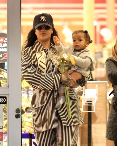 Rihanna z synem. Ma na sobie garnitur w czarno-białe prążki i czapkę z daszkiem oraz okulary przeciwsłoneczne. Syn ma beżowy komplet z dzianiny. Wychodzą razem ze sklepu.