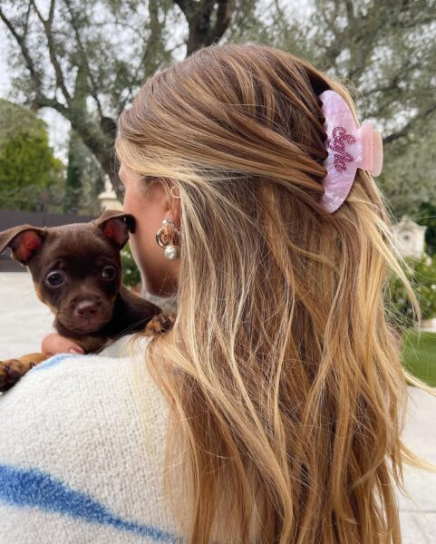 Sofia Richie Grainge w modnej fryzurze na lato 2025 z różową klamrą. Celebrytka stoi tyłem, trzyma na rękach szczeniaka.