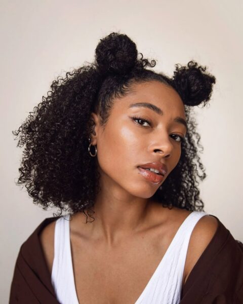 Kobieta z afro we fryzurze typu space buns na lato 2025.