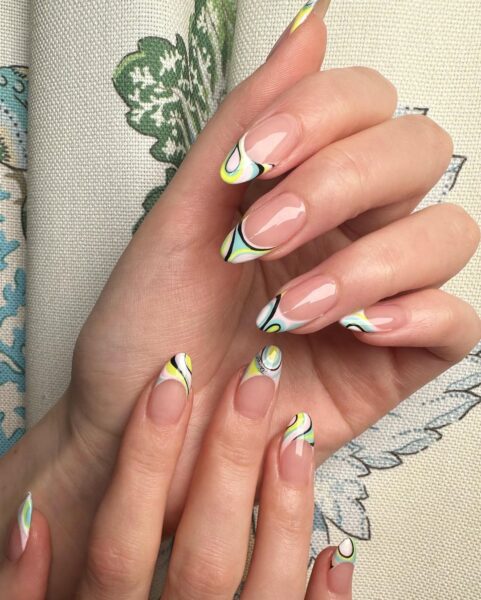 Kobiece dłonie ze stylizacją typu french manicure. Końcówki paznokci są pomalowane na kolorowy Pucci print.