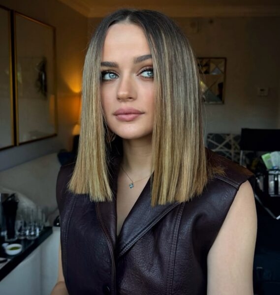 Joey King z modnym cięciem typu clavi cut – prostymi włosami o średniej długości, sięgającymi do obojczyka. Aktorka patrzy w prawo, ma na sobie skórzany strój.