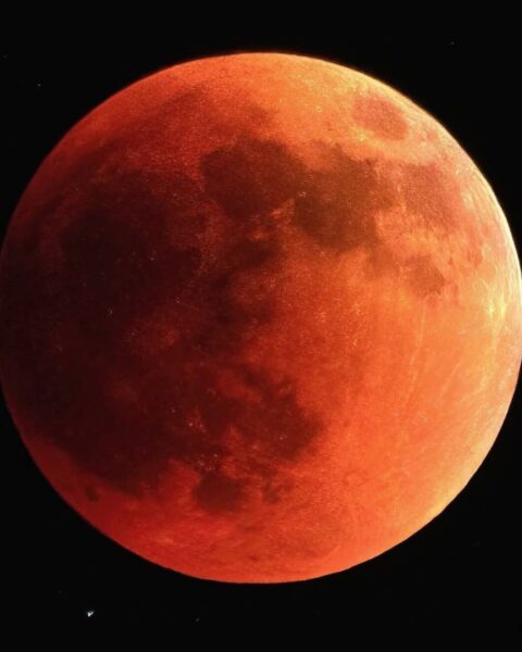 Zdjęcie nocnego nieba z wielkim Księżycem świecącym na czerwono.