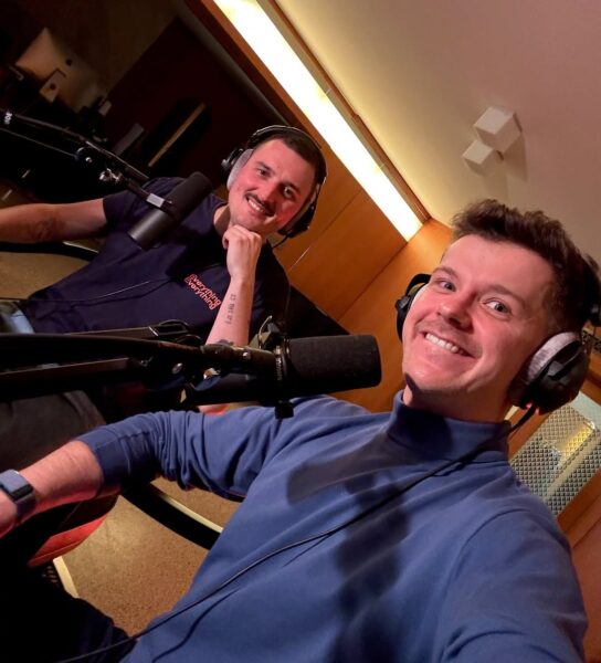 Na zdjęciu Radosław Kotarski i Dawid Podsiadło. To gospodarze jednego z najlepszych podcastów gwiazd: Podsiadło Kotarski Podcast. Na zdjęciu siedzą w słuchawkach z mikorofonami przed twarzą.
